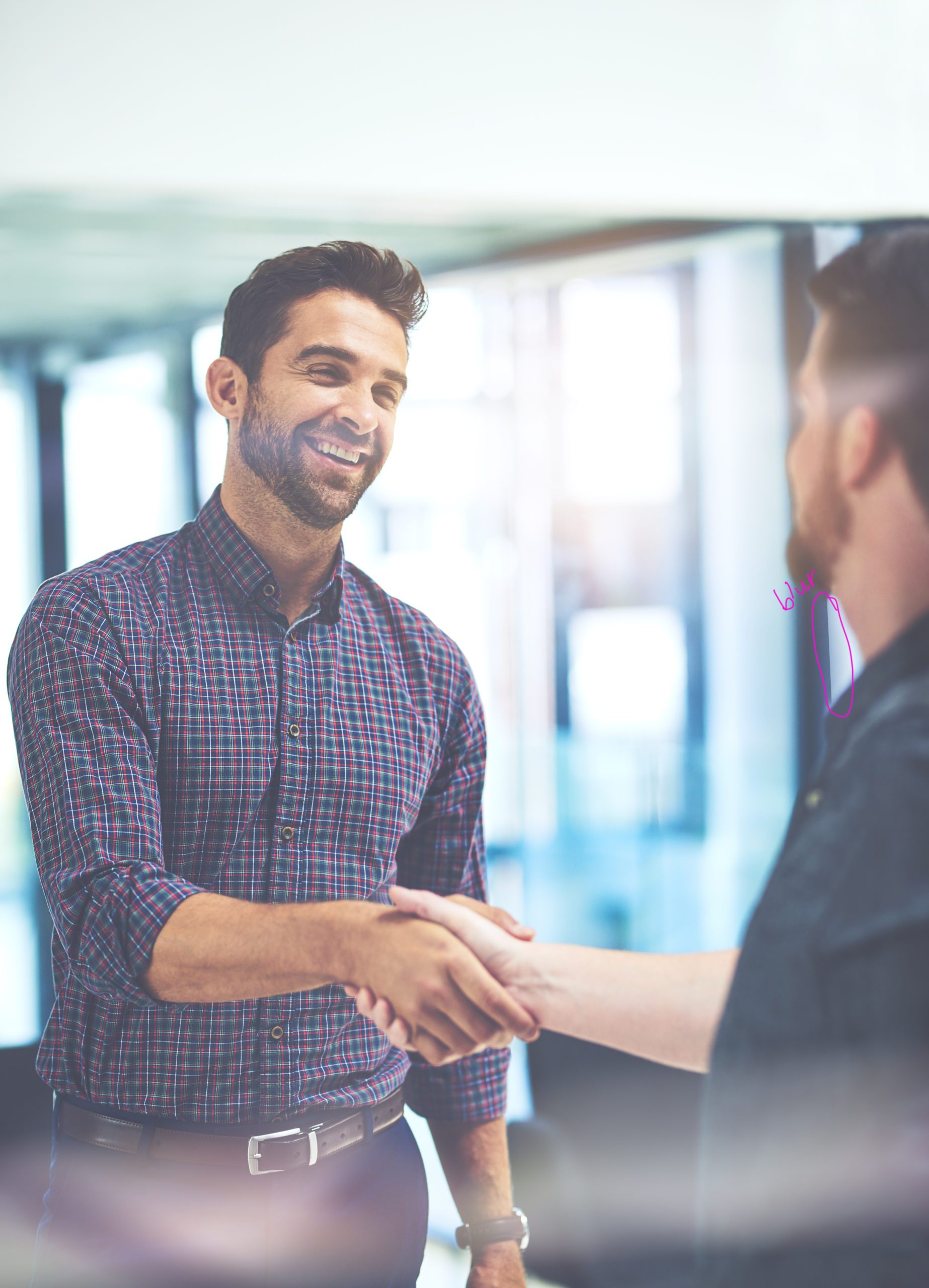 Im so keen to merge our ideas together. Shot of two young businessmen shaking hands in an office